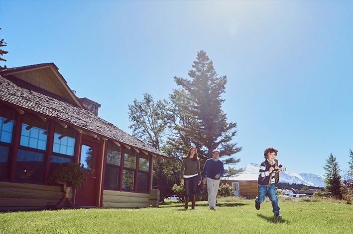 Parents and a young son walking on the grass in front of the Homestead House at st. Mary Village