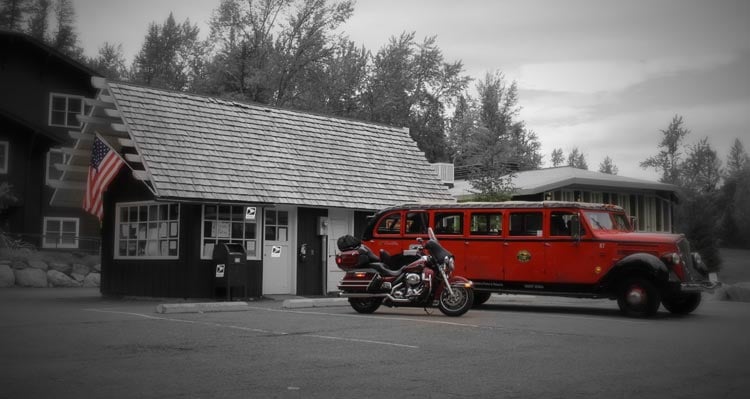 A red bus sits in front of a small wooden building