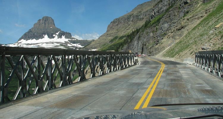 A view on the Going-to-the-Sun Road towards green mountain sides and snow-covered mountains.