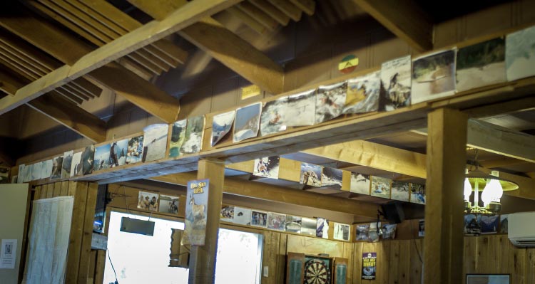 The wall inside a wooden bar is covered with historic photos of adventure.
