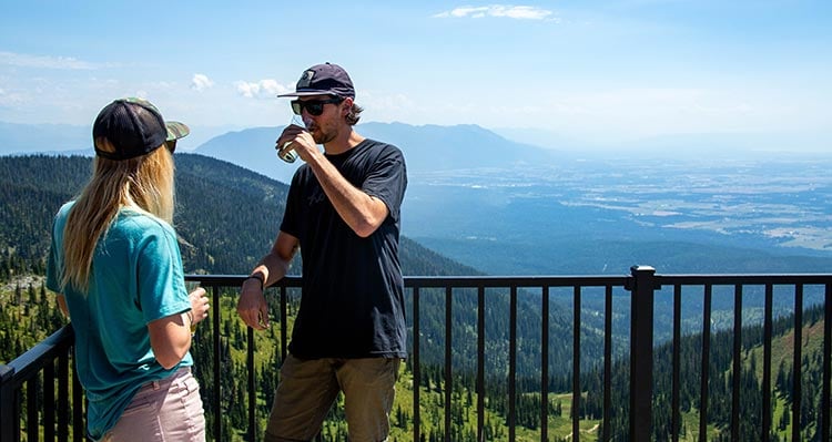 Two people stand on a mountaintop balcony.