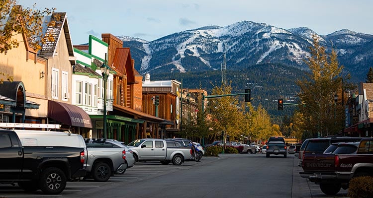 A busy street in Whitefish, Montana in the winter with a ski hill in the distance.