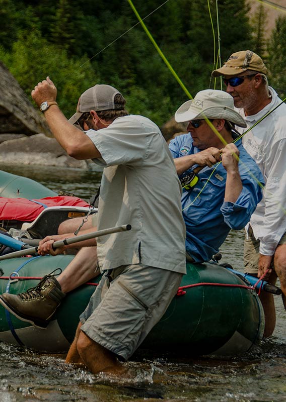 Three men grapple with their fishing gear, reeling in a catch