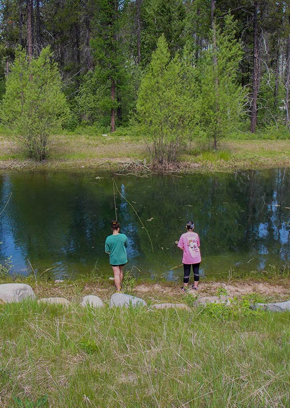 Several people practice fishing in a pond.