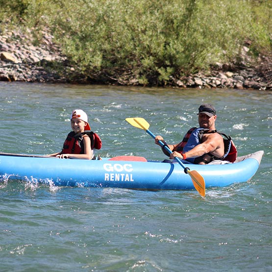 Father and son in a blue double kayak in the water.