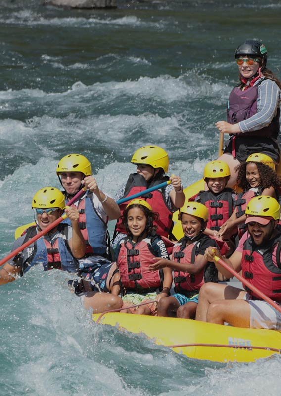 A large raft in water, full of adults and kids.