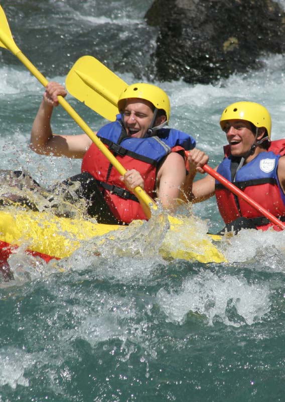 Two kayakers in a splashing river