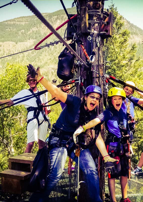A group of zipline riders stand atop a tree-top platform 