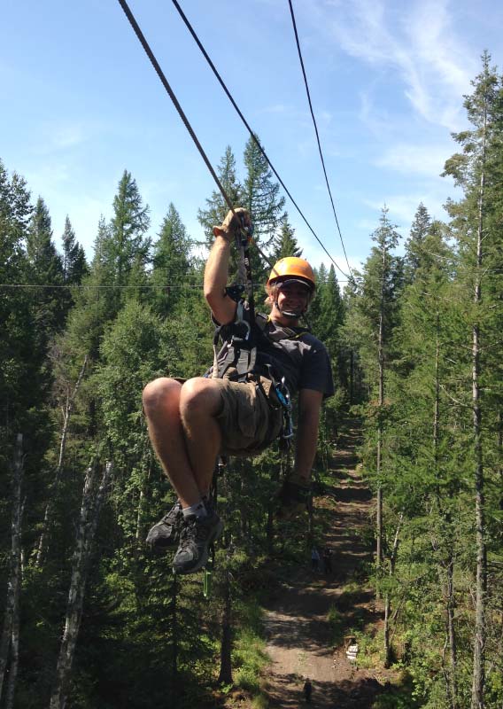 A zipline rider swoops between trees.