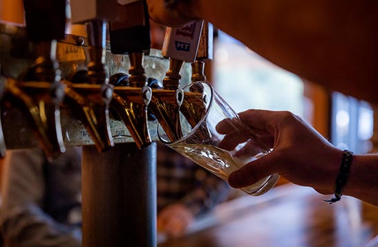 A hand fills a glass of beer from a dispenser