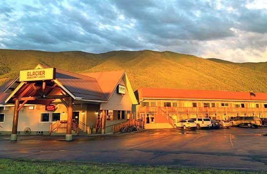 Two motel buildings nestled between conifer trees.