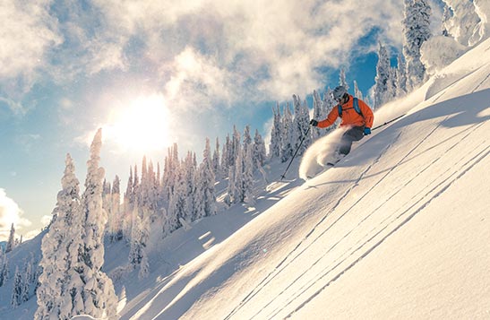 Two people on skis go down a snowy hill 