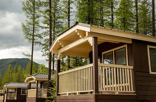 A green cabin and picnic table with camping gear on it.