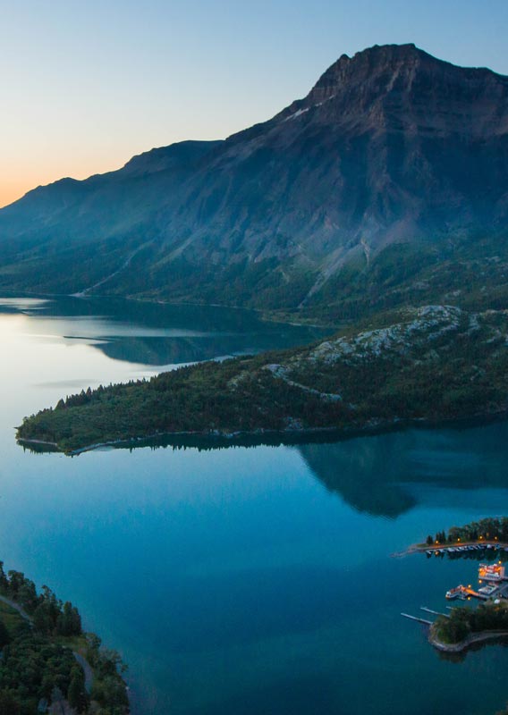 The Prince of Wales Hotel overlooks Upper Waterton Lake. Mountains and grasslands in the distance