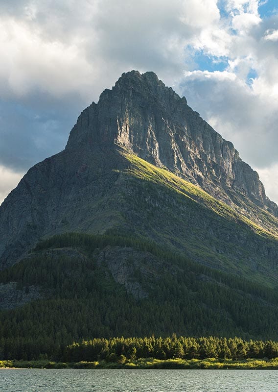 A cliffside and mountain rise above a lake