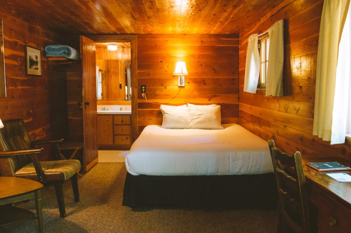 A bed and a lounge area in a wooden cabin.