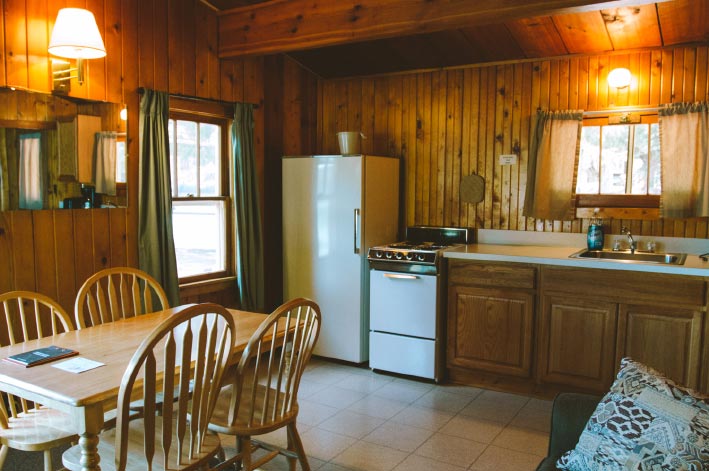 A rustic kitchen and dining area inside a wooden cabin.