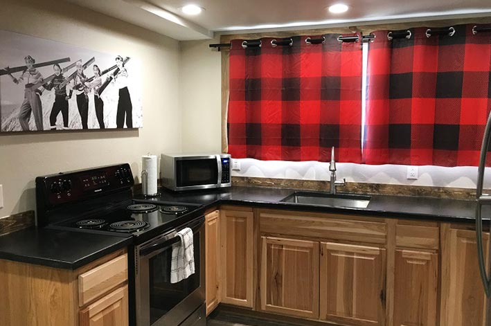 A hotel room kitchen with buffalo check curtains.