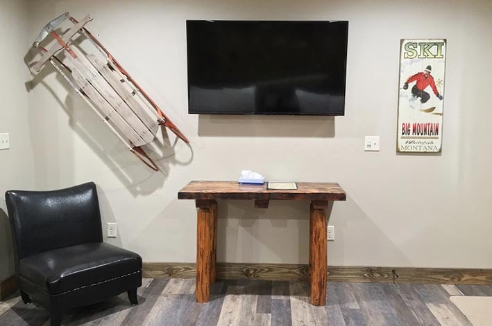 A television mounted on a wall above a wooden table.