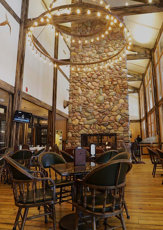 A restaurant dining room featuring a large stone fireplace.