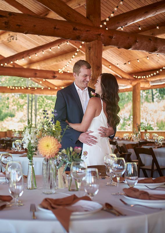 A bride and groom embrace in a partially outdoor dining area.