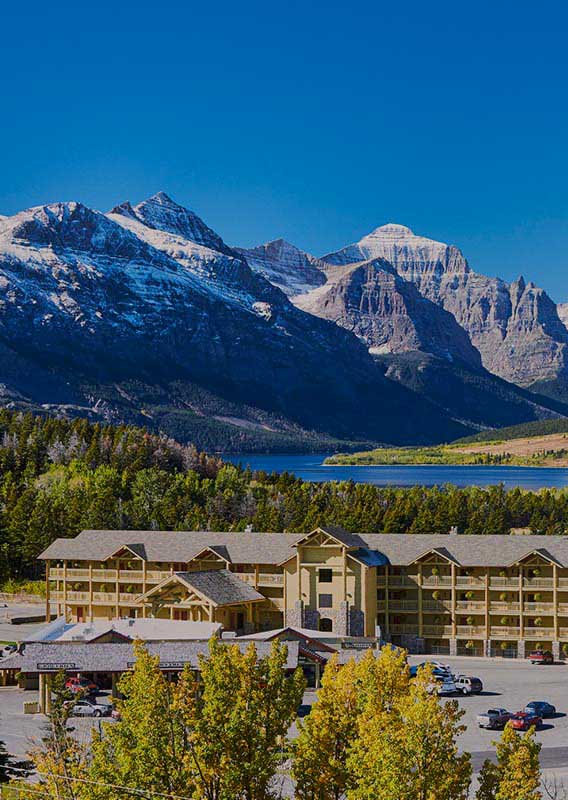 A lodge nested by a lake as mountains rise from plains