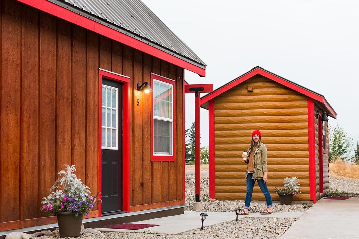 https://www.glacierparkcollection.com/GlacierParkInc/media/Images/Lodging/St-Mary-Lodge-Resort/Tiny%20Homes/Gallery/GI-st-mary-village-tiny-homes-wood-woman-coffee.jpg
