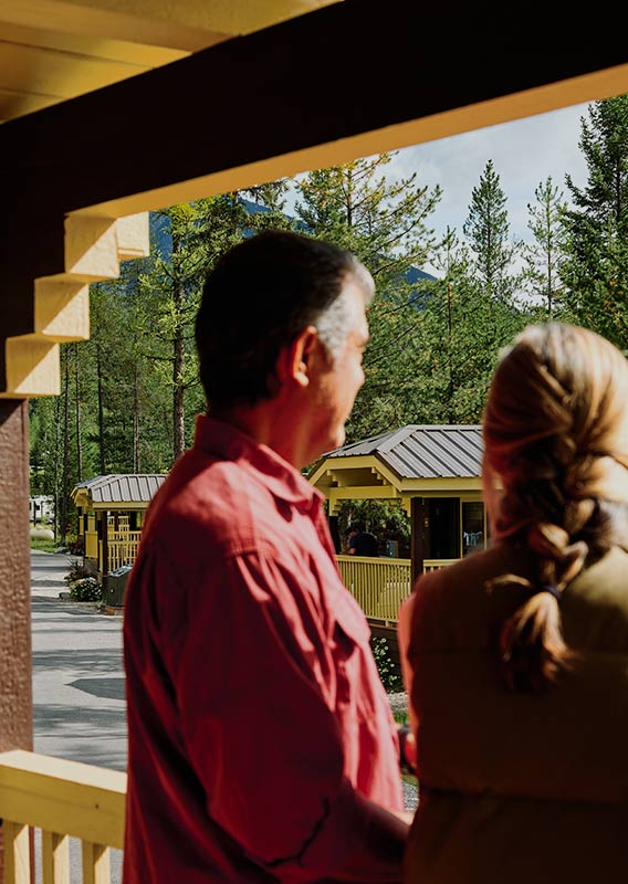 Two people look away out from a cabin porch.