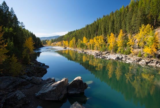 A river runs between tree-covered shores and hillsides.