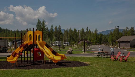 Children's play equipment in grassy park as kids bike along the quiet road