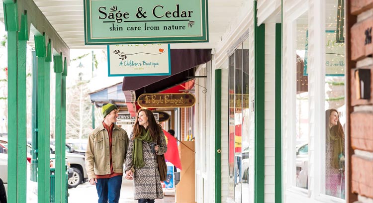 A couple walks on a covered walk alongside shops.