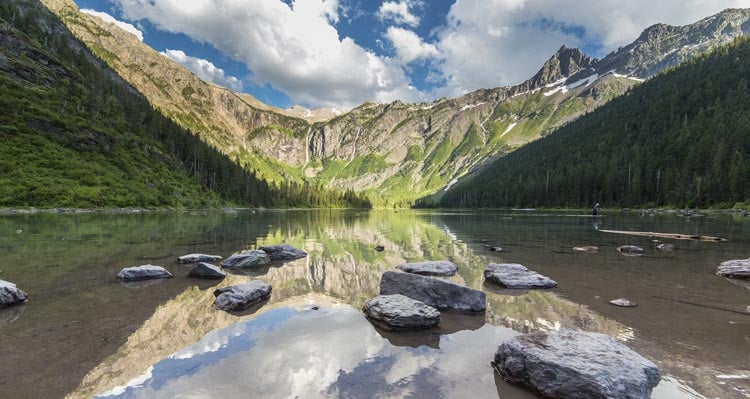 A view of a calm alpine lake in a rocky, tree-covered bowl.