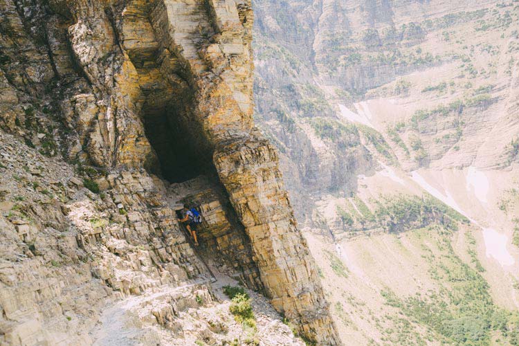 A hiker makes a small climb into a natural tunnel