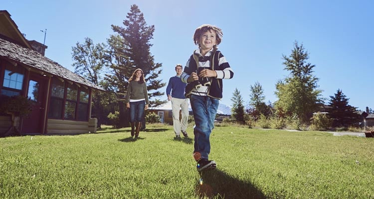 A child runs on grass as parents walk behind at St. Mary Village