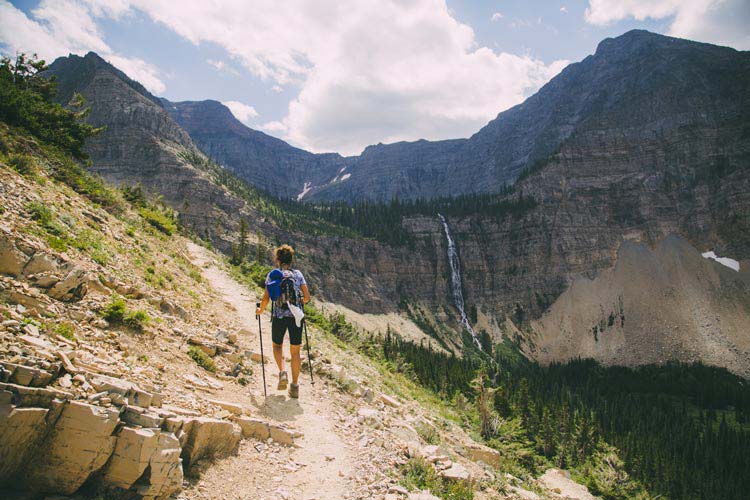 A hiker walks high above a valley on a trail