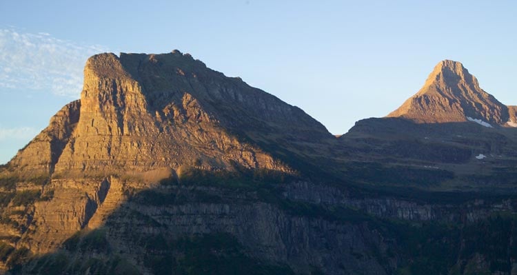 The morning sun shines brightly on one face of the mountains as the other side remains in shadow.