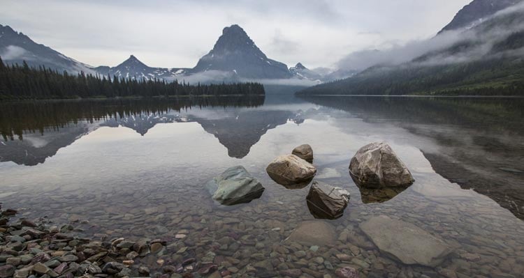 A view across a calm lake towards mountains and valleys.