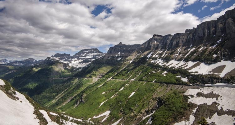 Mountainsides covered with snow and trees sweep alongside a wide valley.