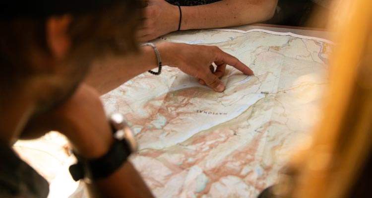 People look at a map and point at destinations among lakes and mountains.