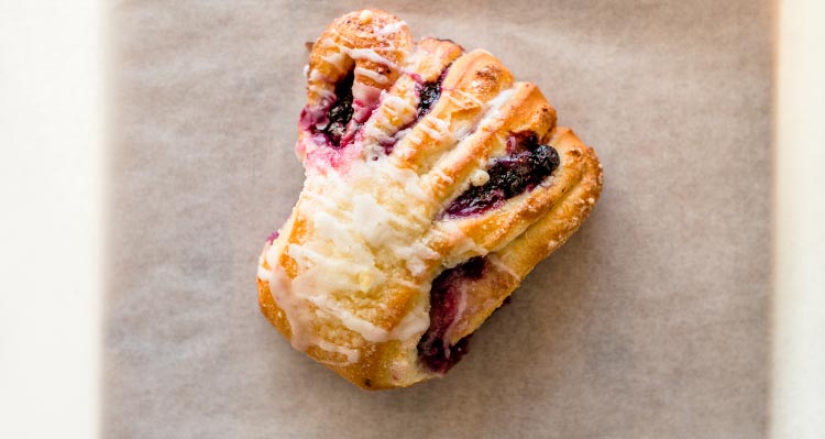 A pastry filled with purple jelly on parchment paper.