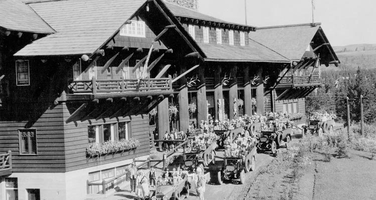 A historic image of cars outside a large wooden lodge.