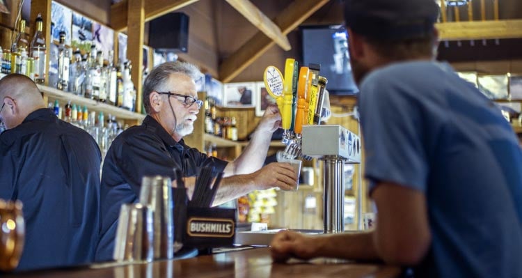 A bartender pours a beer from a tap.