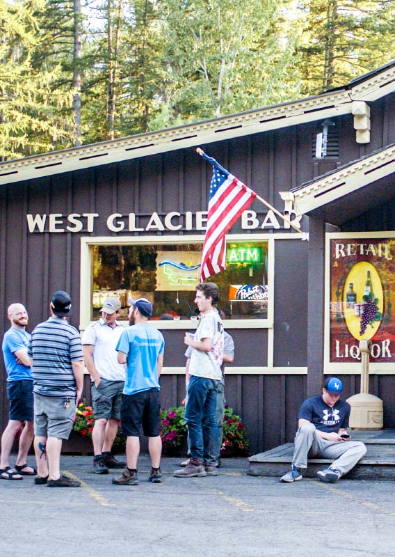 A crowd stands around outside Freda's Bar, a rustic wooden building.