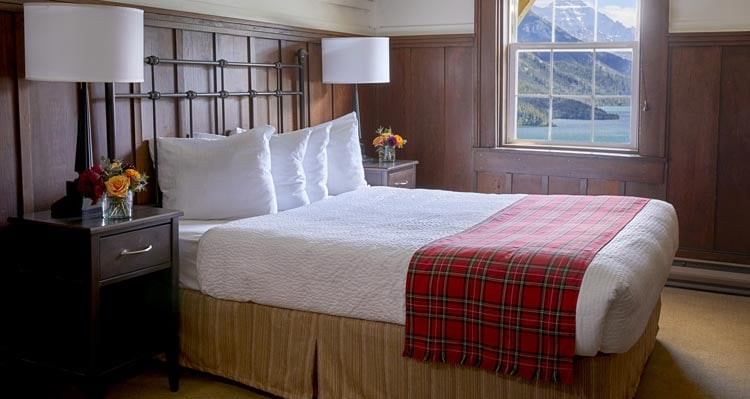 A guest room with a tartan blanket draped over the bed.