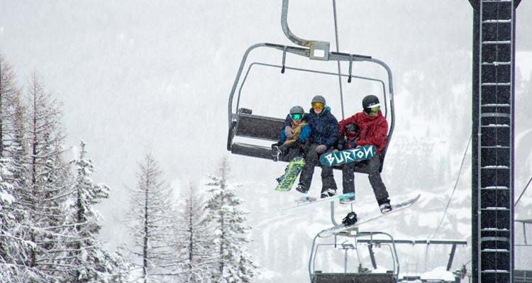 A family rides a ski lift on a snowy day.