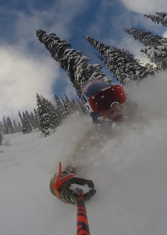 A selfie of a man skiiing through deep powder snow