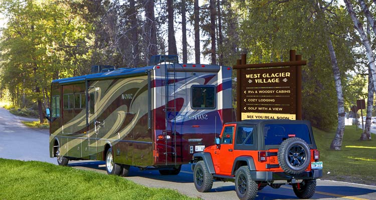 An RV pulling a Jeep drives into the West Glacier RV Park
