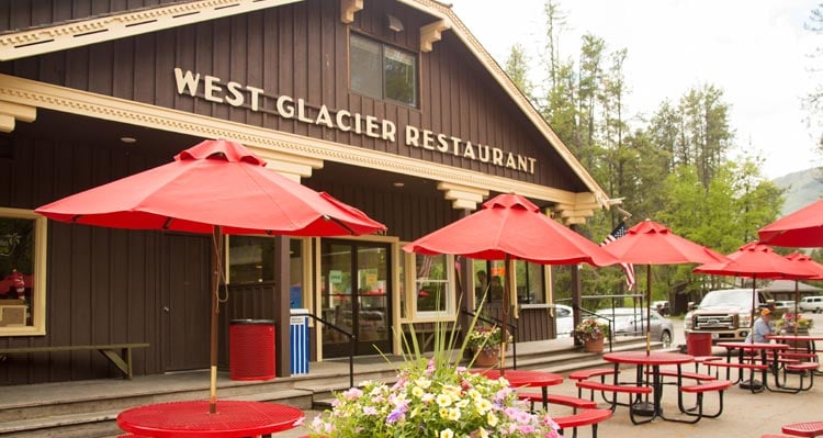 A wooden restaurant building with a patio of red umbrellas