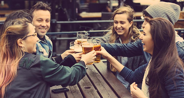 A group of friends raise their beers in a cheers.