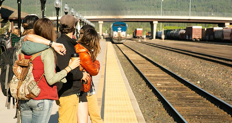 A group of people watch an Amtrak train roll into Whitefish.